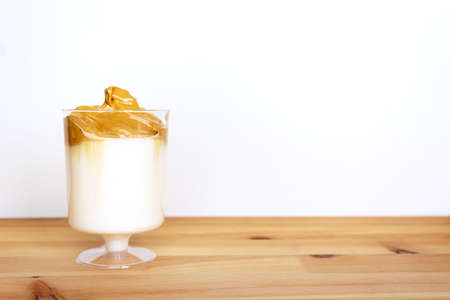 Dalgona coffee in glass on wooden table. Copy space. Amazing delicious trendy korean whipped drink. Dalgona coffee.の写真素材