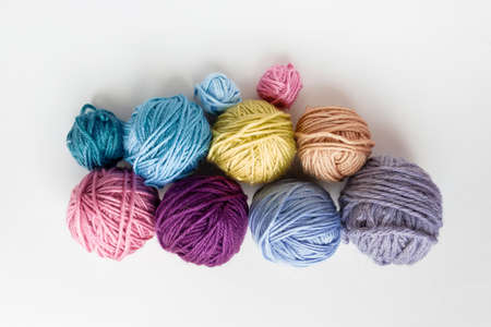 Multi-colored skeins of woolen threads. Different sizes. Top view of light background. Many colorful...