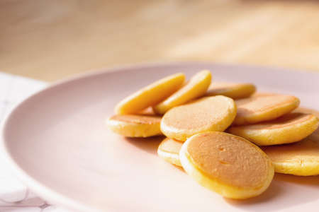 Amazing delicious trendy tiny pancakes cereal on gently pink plate. Wooden table background.の写真素材