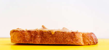 Peanut paste butter sandwich on toasted bread on yellow background. Close-up. Copy space for your...