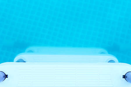 Plastic white portable staircase to country small pool. Blue water in plastic pool in summer sunny...