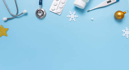 Christmas card with stethoscope, thermometer, pills, snowflakes, and festive balls on blueの写真素材