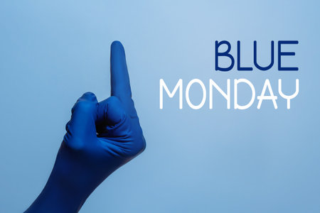 Blue monday concept. The most depressing day of the year. Blue gloved hand showing fuck to this day.の写真素材