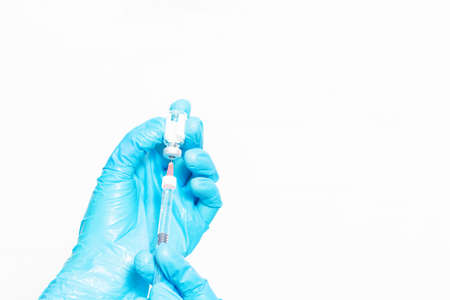 Hands in blue protective gloves. Doctor or nurse filling medicine from ampoule into syringe. Copy...