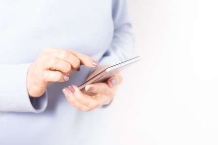 Elderly hands holding mobile cell phone. Unrecognizable old woman browsing news feed at cellphone....