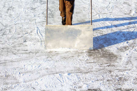 Toddler boy cleaning snow with special shovel on nature ice rink in the backyard.の写真素材