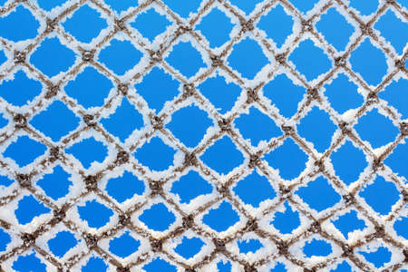 Net covered with snow against blue sky on clear winter day. Natures minimalism. Cose-up. Abstract...