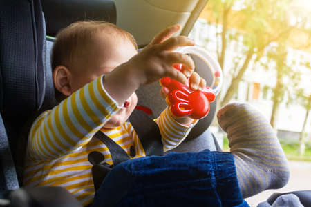 Happy baby sitting in car seat, playing.の写真素材
