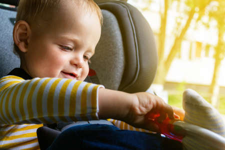 Happy baby sitting in car seat, playing.
