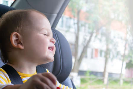 Happy baby boy sitting in car seat.の写真素材