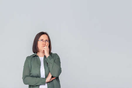 Small business owner with thoughtful face in casual clothes. Business woman portrait on grey...