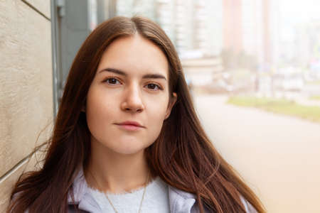 Young caucasian woman looking to the camera. Beautiful girl with brown loose hair walking down the...