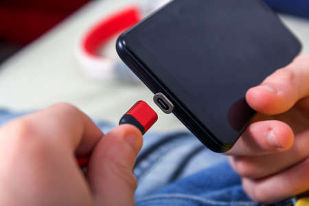 Red magnetic phone charger in hands. Process of connecting magnetic charger to cell phone jack....