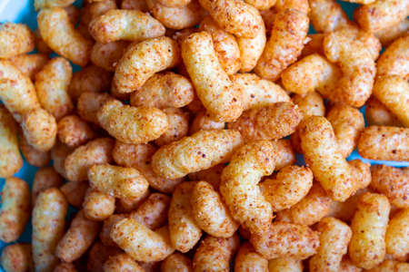Puffed corn peanuts snacks served on blue plate. Close-up. Selective focus. Cheese flavored puffed...