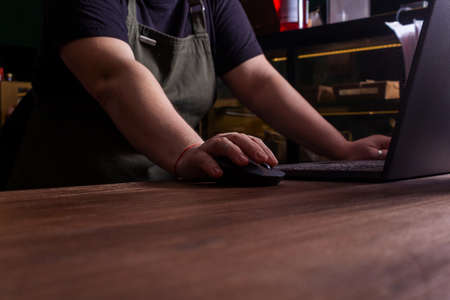 Unrecognizable caucasian coffee shop owner working on computer on online order. Close up hand on...