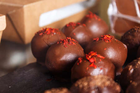 Cheese candies in chocolate coating on counter. Handmade chocolates with different decorations . Free place to put your price.の写真素材