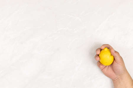 Fresh healthy Lemon in the hand above grey marble table background with copy space