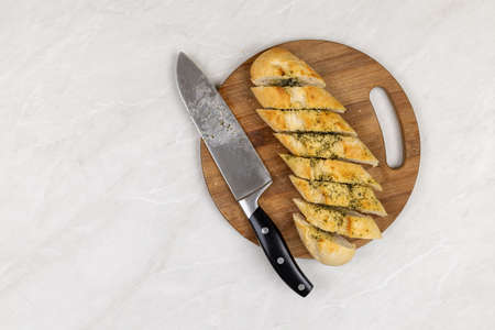 Baked and sliced bruschetta bread with garlic and spices served on the wooden board with copy space.
