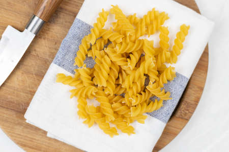 Raw pasta on the kitchen table with dishcloth wooden board knife and copy space.の写真素材