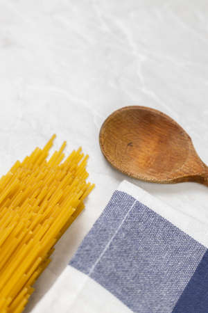 Raw pasta on the kitchen table with dishcloth wooden board knife and copy space.の写真素材
