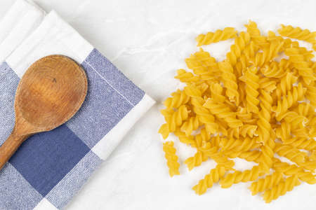 Raw pasta on the kitchen table with dishcloth wooden board knife and copy space.の写真素材