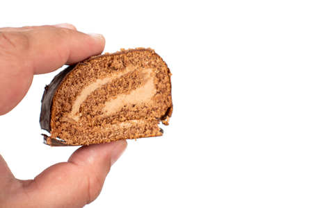 Chocolate Roll Cake In The Hand Above White Background With Copy Space.
