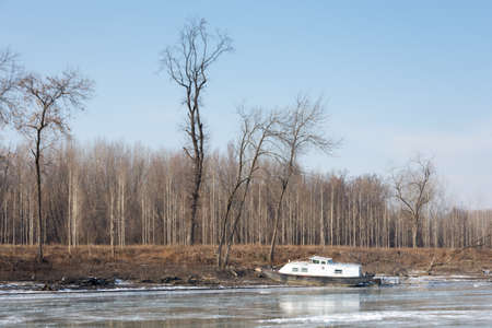Frozen river with forest trees and boat