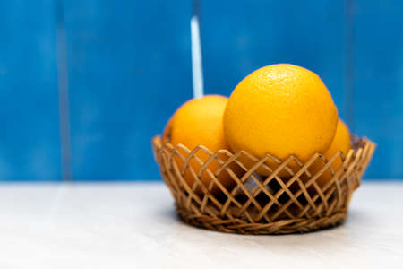 Oranges in the basket with blue wooden boards background and copy space.