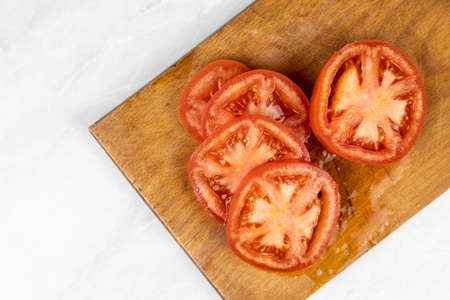 Sliced fresh tomato on the wooden cutting board with copy space.の写真素材