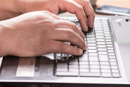 Adult mans hand on the keyboard of lap top.