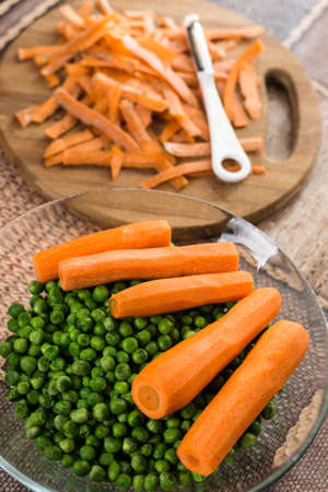 Cooked green peas with cooked carrot on the wooden board.の写真素材
