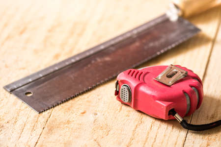 Hand saw construction meter on the wooden planks background.の写真素材