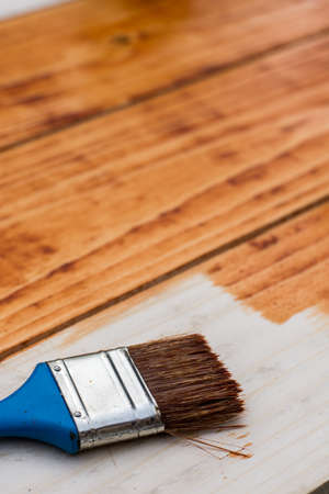 Paintbrush on the fresh painted wooden planks board.の写真素材