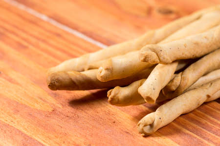 Pile of grissini sticks on the wooden board background.
