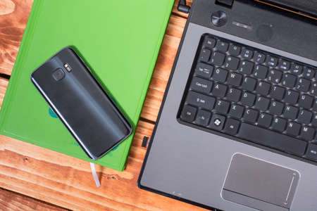 Flat lay lap top computer with cup of coffee and mobile phone on the wooden background.の写真素材