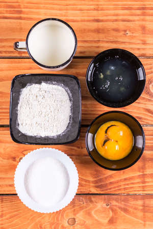 Flat lay above sugar flour egg white yolk and milk. Ingredients for american pancakes recipe.