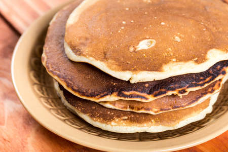 Closeup macro of american pancakes stacked on the plate over rustic wooden background table.