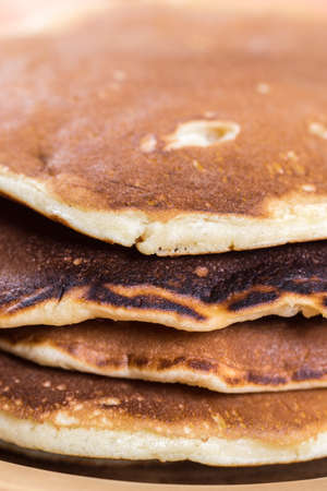 Closeup macro of american pancakes stacked on the plate over rustic wooden background table.