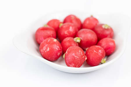 Red radishes on the white bowl with copy space.