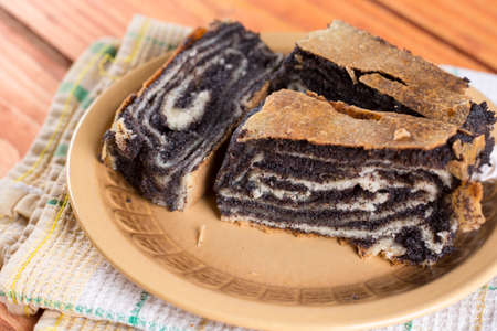Poppy seed roll cake slices on the wooden background.の写真素材