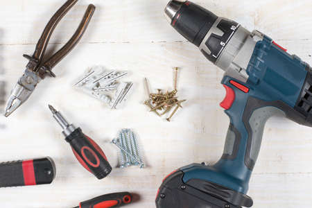 Acu drill screwdriver rachet and tools flat lay over wooden background.