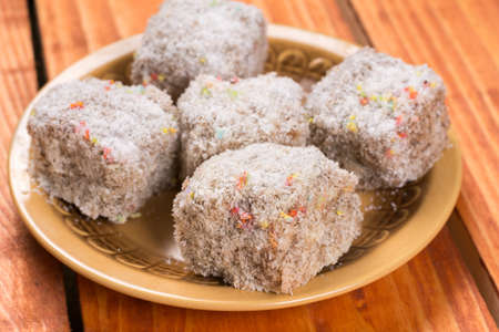 Chocolate cookies with coconut served on the plate over wooden background.