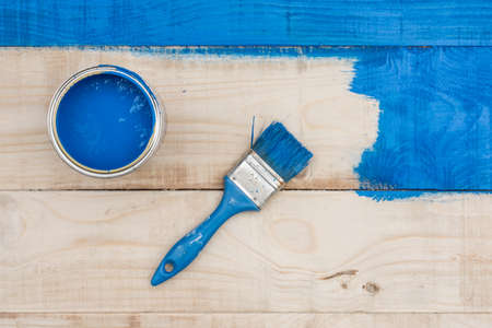 Flat lay above bucket with blue paint and brush on the wooden board.の写真素材