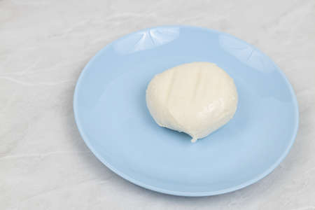 Mozarella cheese served on the blue plate above white marble table.の写真素材