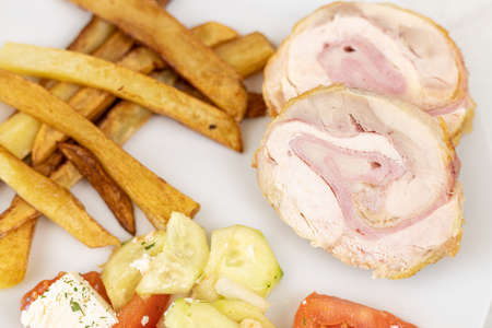 Served rolled chicken with tomato salad with mozarella and french fries.の写真素材