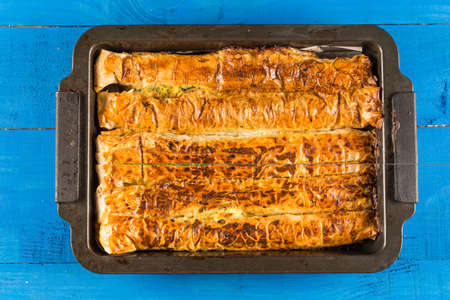 Flat lay above homemade domestic crisp pie above blue wooden planks background.