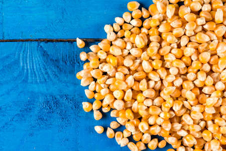 Pile of raw popcorn above blue wooden background with copy space.の写真素材