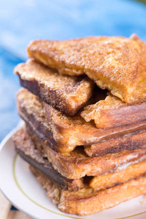 Flat lay pile of triangled french toast above blue wooden background table.