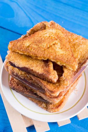 Flat lay pile of triangled french toast above blue wooden background table.