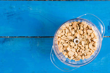 Flat lay bowl with blanched peanuts above blue wooden backgroundの写真素材
